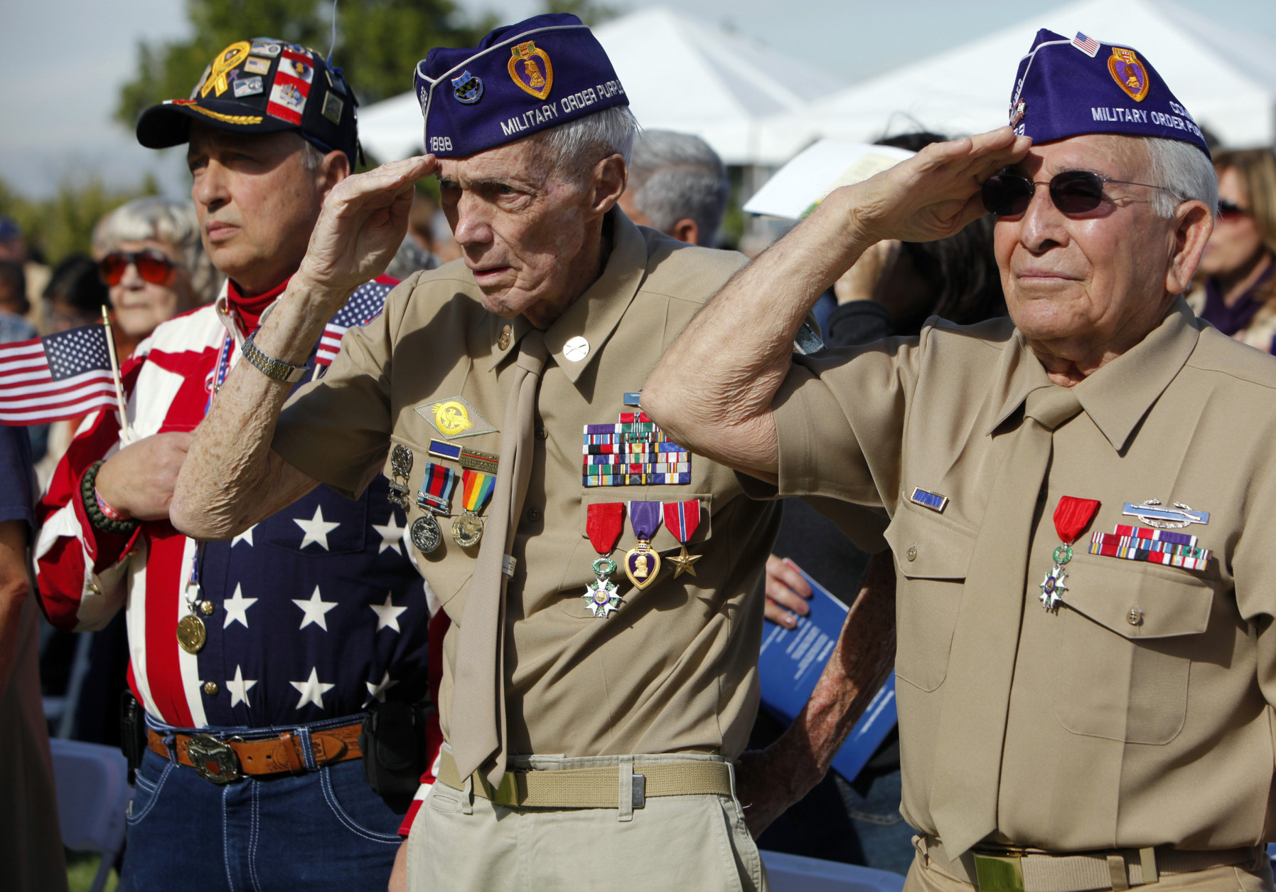 Peter Howenstein, middle, and Joe Govea, right, veterans of World War II and members of the military Order of the Purple Heart salute during Veterans Day ceremonies at Forest Lawn Hollywood Hills Memorial Park in Los Angeles Friday, Nov. 11, 2011. At far left is Paul Boghossian with Operation Gratitude. (AP Photo/Damian Dovarganes)