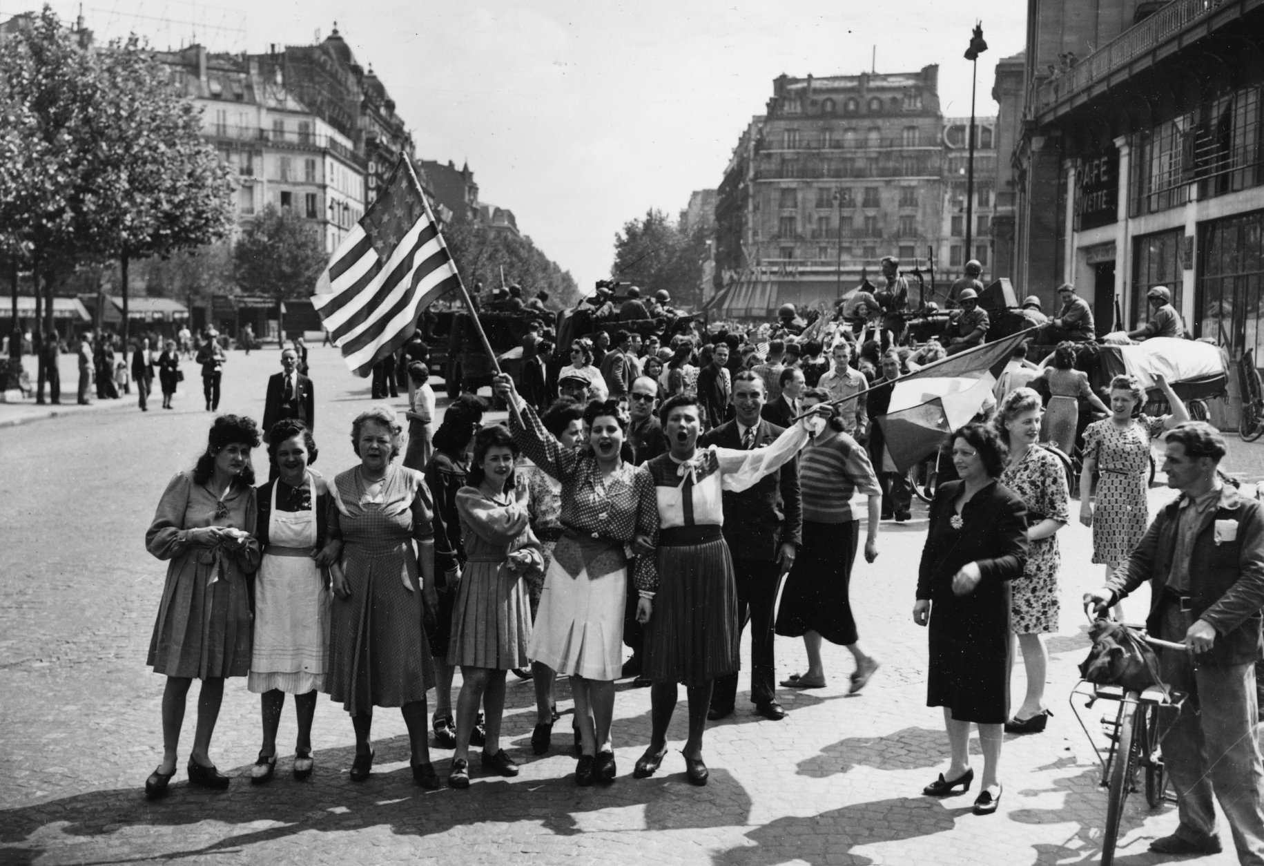 French civilians with their hastily made American and French flags sing the "Star Spangled Banner" as they greet U.S. and Free French troops entering Paris, France, Aug. 25, 1944, after Allied liberation of the French capital from Nazi occupation in World War II.  (AP Photo/Harry Harris)
