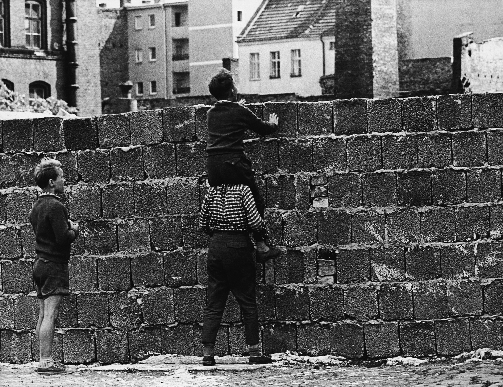 On August 13, 1961, East Germany sealed off the border between Berlin's eastern and western sectors; within days, the Communist authorities began building a wall that would stand for the next 28 years. Here, a boy sitting on the shoulders of another child peers at the Liesen Street in Wedding, West Berlin. (AP Photo/Werner Kreusch)