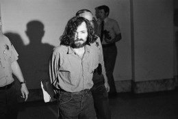 Charles M. Manson, squinting in the glare of a film cameraman's floodlight, marches to court, Aug. 20, 1970, for a hearing on his claim he is being mistreated by deputies in the Los Angeles County Jail.  After the hearing his trial on murder charges resulting from the slayings of actress Sharon Tate and six others was scheduled to resume. (AP Photo/George Brich)