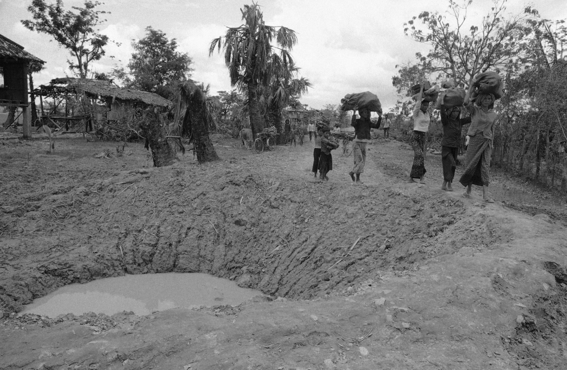On this date in 1973, U.S. bombing of Cambodia came to a halt. Here, Cambodian villagers walk around bomb crater in road near embattled Takeo 42 miles southwest of Phnom Penh in Cambodia  May 17, 1973.  (AP Photo/Chhor Yuthy)