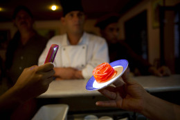 In this Oct 18, 2013 photo, a professional cook holds up a 3D gelatin flower desert during a meeting of Cuban chefs in Havana, Cuba. In the past two years, thanks to the economic reform initiated by the government, thousands of "paladares," the name given to privately-owned restaurants, have populated the island: from very elegant spaces installed in old restored mansions decorated with works of art, to modest roadside cafes. (AP Photo/Ramon Espinosa)