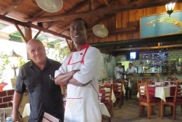 This May 14, 2015 photo shows Pedro Tejeda Torres, left, and Jonathan Nyamudihura, owner and chef at Cafe Ajiaco in Cojimar, just east of Havana, Cuba. The privately owned restaurant specializes in offering refined versions of traditional Cuban recipes. (AP Photo/Beth J. Harpaz)