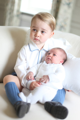 This image made available by Kensington Palace Saturday, June 6, 2015, taken by Kate, Duchess of Cambridge, at Amner Hall, eastern England in mid-May 2015 shows Britain's Princess Charlotte, right, being held by her brother, 2-year-old, Prince George. Britains royals have been photographed by some of the world's leading photographers. But Prince William and Kate are continuing a more informal tradition begun two years ago with the first official portrait of Prince George, taken by his grandfather Michael Middleton. Charlotte was born May 2 and is fourth in line to the throne. (Duchess of Cambridge via AP)  MANDATORY CREDIT