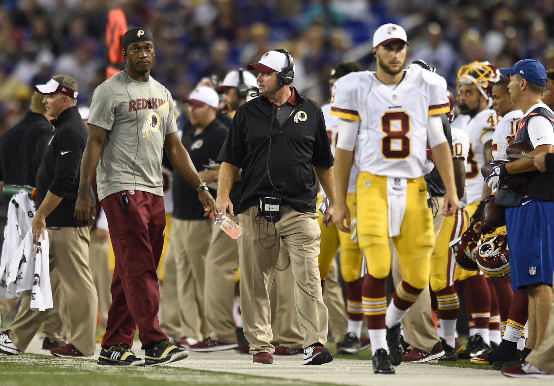 Washington Redskins head coach Jay Gruden, center, walks on the sideline behind quarterbacks Robert Griffin III, left, and Kirk Cousins (8) in the second half of a preseason NFL football game against the Baltimore Ravens, Saturday, Aug. 29, 2015, in Baltimore. (AP Photo/Gail Burton)