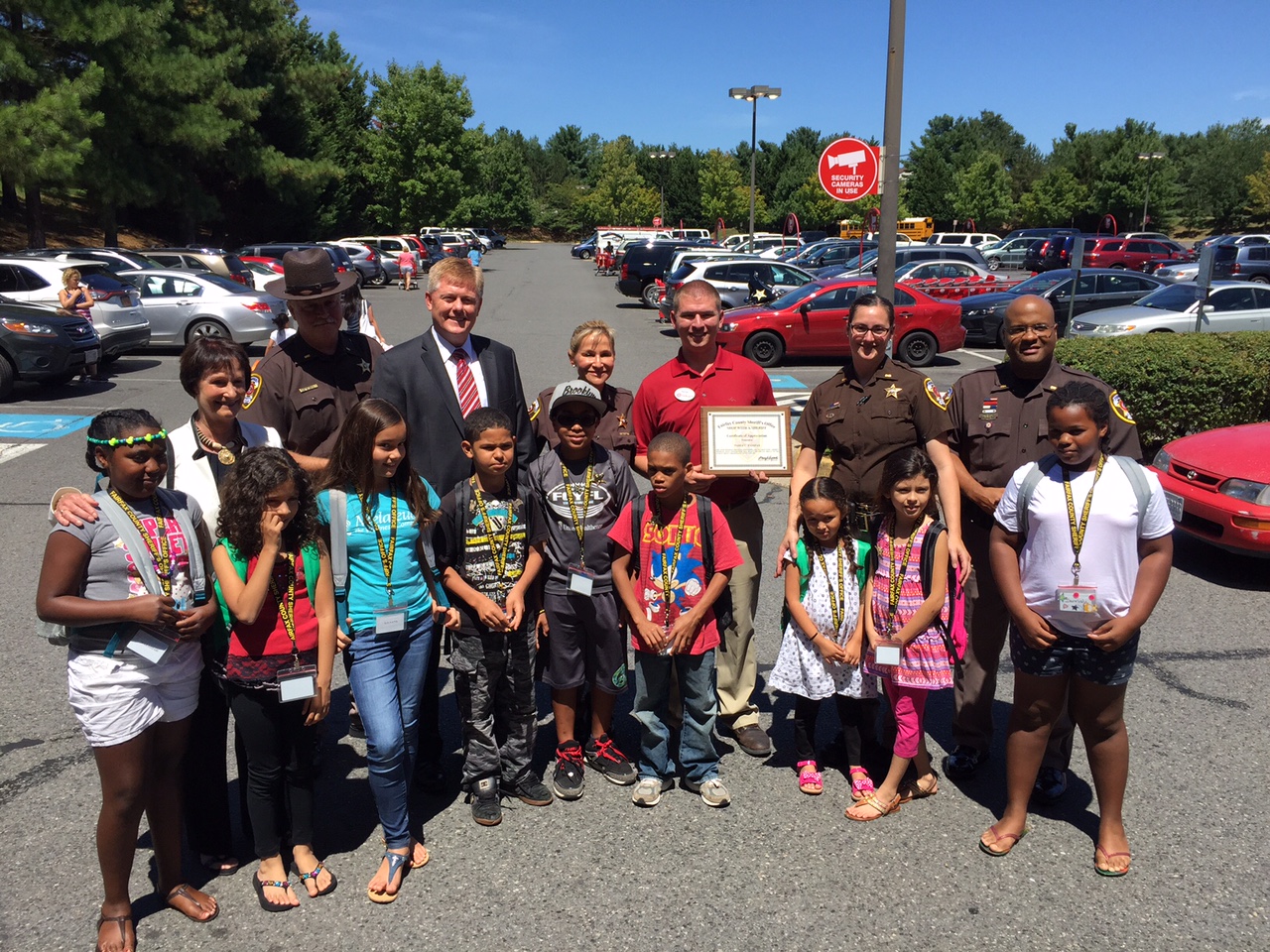 Just some of the 40 homeless children being treated to a shopping spree pose with Sheriff's deputies and community leaders, including Fairfax County Supervisors Chair Sharon Bulova, Supervisor John Cook, Sheriff Stacey A. Kincaide and Nathan Cooke of Target. (WTOP/Kristi King)