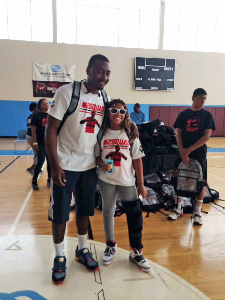 Rising sixth grader Heather Lee, of Stuart Hobson Middle School, D.C. poses for a photo with Wizards guard John Wall during a backpack giveaway event Saturday, Aug. 15, 2015. (Dick Uliano/WTOP)
