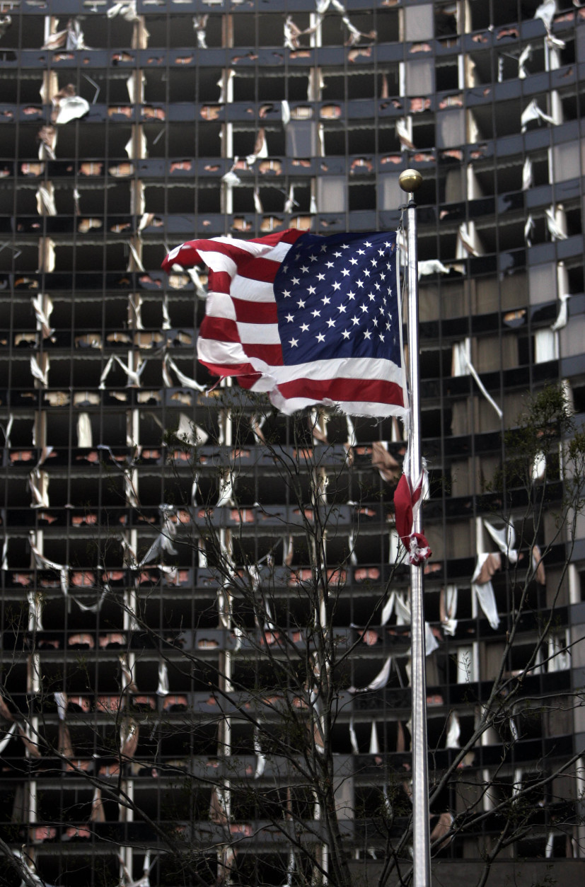 A tattered U.S. Flag flies in the foreground of the Hyatt, in New Orleans, Monday, Aug. 29, 2005, where dozens of windows were blown out when Hurricane Katrina made land fall. ( (AP Photo/Eric Gay)