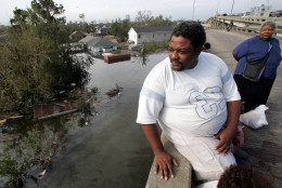 Thomas Green sits atop Interstate-10 in the flooded city of New Orleans on Tuesday, Aug. 30, 2005. Green and his family were rescued from their flooded home in the 8th Ward of the Crescent City by emergency personnel. At right is his wife Quentina.  (AP Photo/Dave Martin)