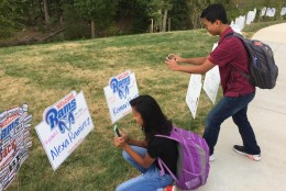 Alexa and Roman Ramirez take pictures of the welcome signs with their names on them, signed on the back by their parents. (WTOP/Kristi King)