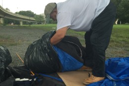 Rafael Cruz packs his belongings in garbage bags ahead of an approaching rainstorm. (WTOP/Andrew Mollenbeck)