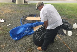 Rafael Cruz packs his belongings in garbage bags ahead of an approaching rainstorm. (WTOP/Andrew Mollenbeck)