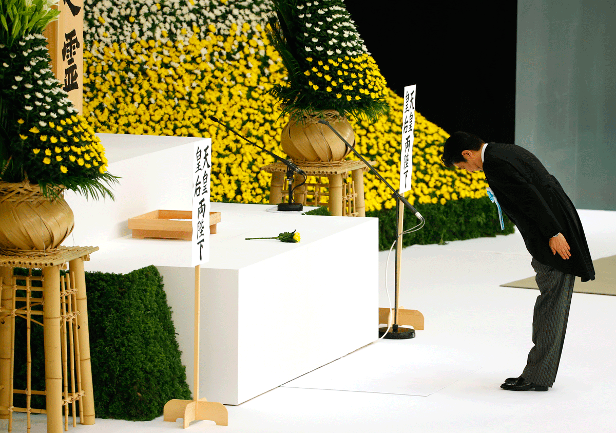 Japanese Prime Minister Shinzo Abe bows before the main altar decorated with huge bank of chrysanthemums as he offers prayers for the war dead during a memorial service at Nippon Budokan martial arts hall in Tokyo, Saturday, Aug. 15, 2015. Japan marked Saturday the 70th anniversary of the end of World War II. (AP Photo/Shizuo Kambayashi)