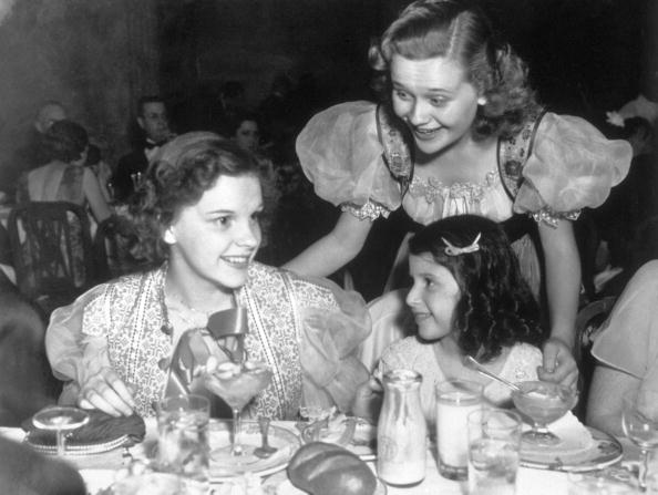 circa 1935:  American singer and actress Judy Garland seated, left, at a children's tea party.  (Photo by Hulton Archive/Getty Images)