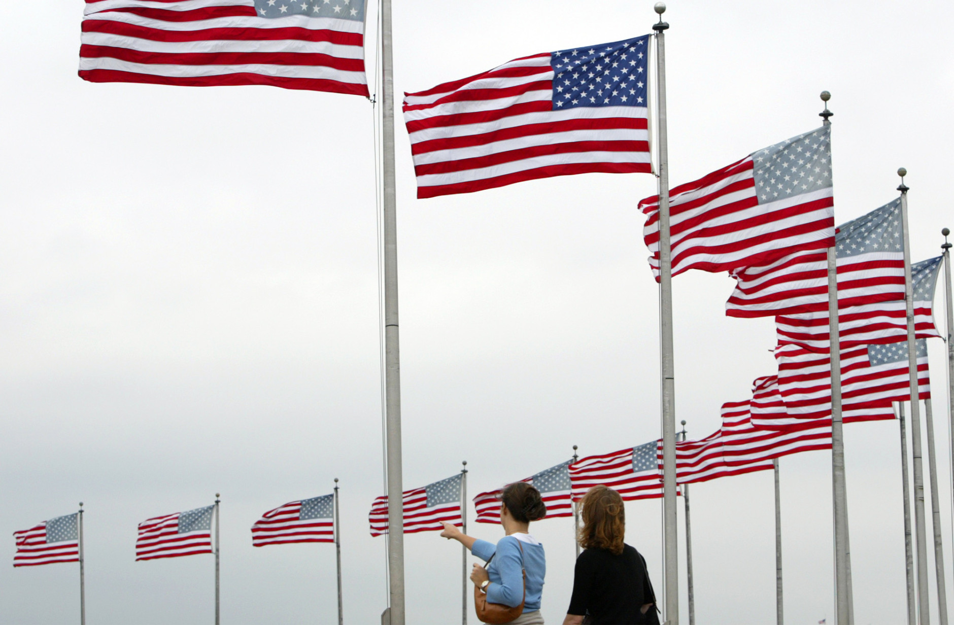 Visitors watch flags blow in the wind around at the Washington Monument Thursday morning, Sept. 18, 2003, as Hurricane Isabel begins to affect the Washington area. (AP Photo/Evan Vucci)