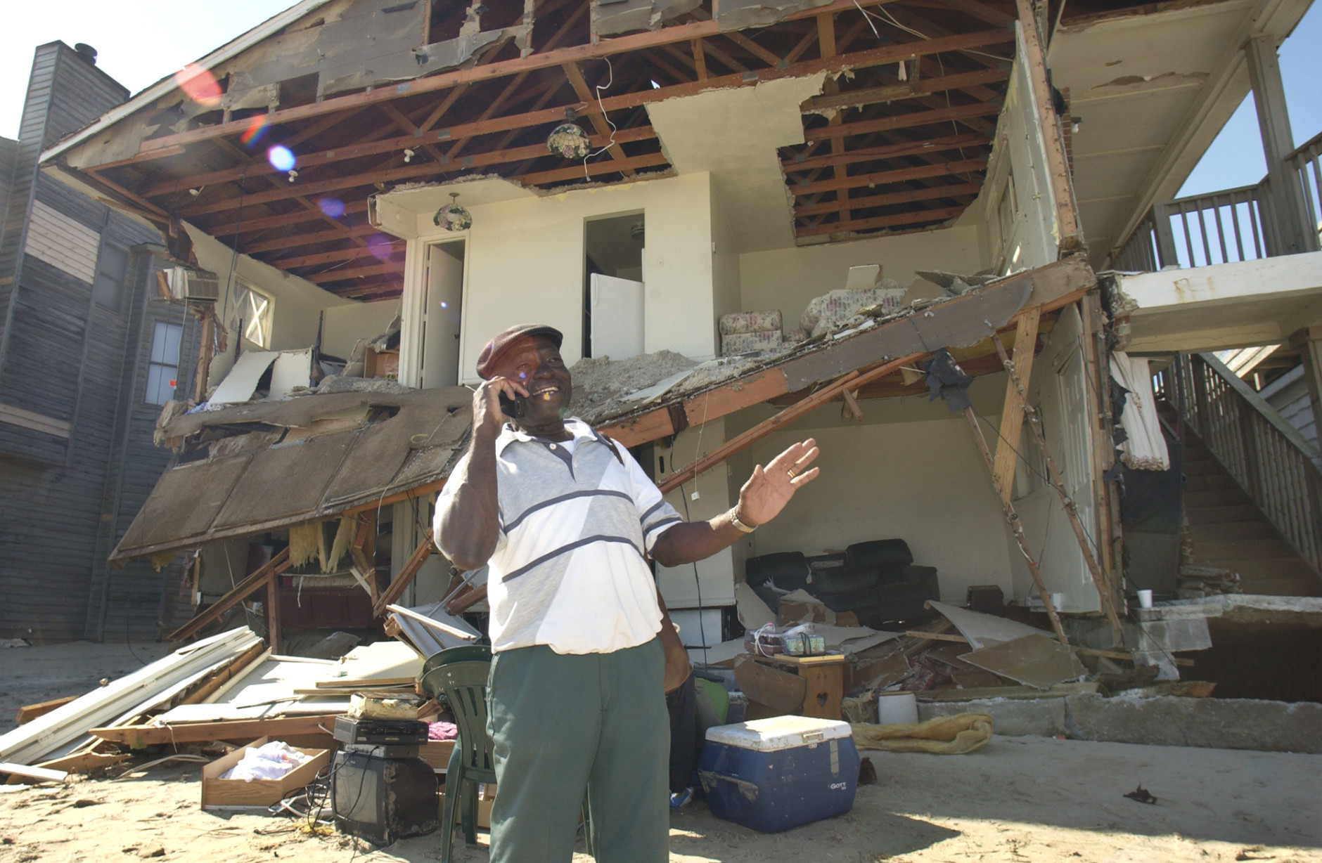 Levi Sabir, of Willoughby Spit, talks on a cellphone to a Red Cross official as he tries to recover belongings from his destroyed ground floor apartment in Norfolk, Va., Friday Sept. 19, 2003. Sabir and his wife were not in the apartment when Hurricane Isabel destroyed it.  The storm battered the area leaving over 3.5 million people without power.   (AP Photo/Steve Helber)