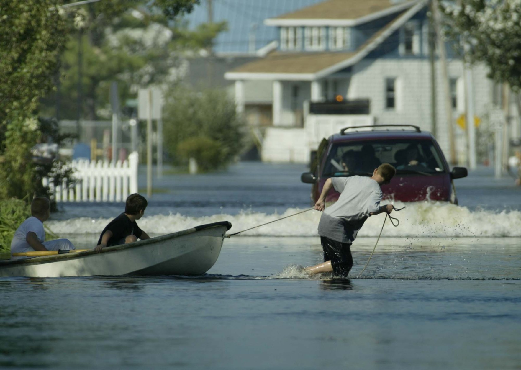 Children pull a boat in front of a water-plowing car in a street in Crisfield, Md., Friday, Sept. 19, 2003, where streets were flooded following Hurricane Isabel. (AP Photo/George Widman)