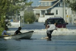 Children pull a boat in front of a water-plowing car in a street in Crisfield, Md., Friday, Sept. 19, 2003, where streets were flooded following Hurricane Isabel. (AP Photo/George Widman)