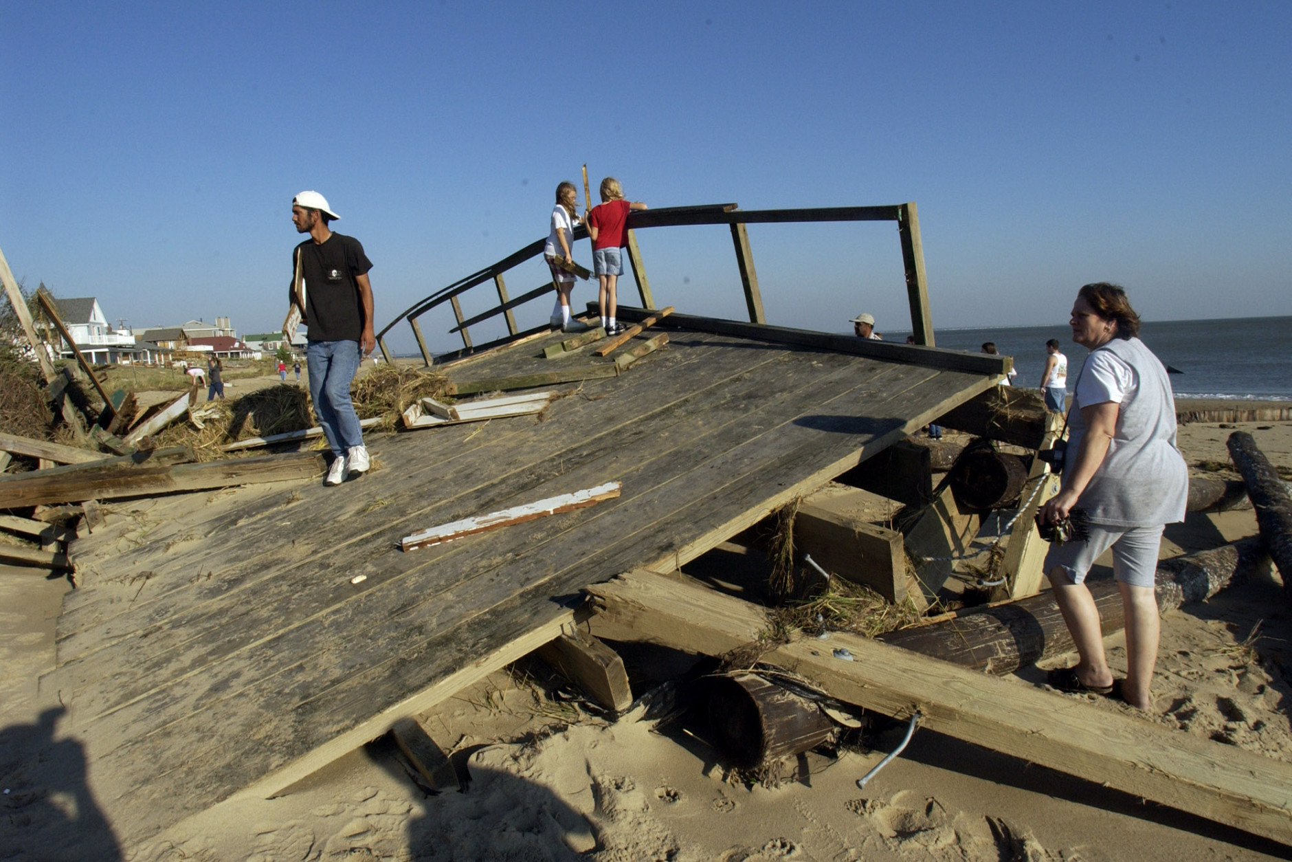 Local residents walk over a section of Harrison fishing pier that washed ashore on the beach in the Ocean View area of Norfolk, Va., Friday Sept. 19, 2003. The pier was built in the 1940's and was destroyed by Hurricane Isabel.  The storm battered the area leaving over 3.5 million people without power.   (AP Photo/Steve Helber)
