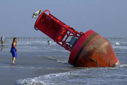 A passerby looks at a large navigation buoy which was beached by the winds and surf of Hurricane Isabel near Rudee Inlet in Virginia Beach, Va., Friday morning Sept. 19, 2003. Hurricane Isabel blew through the area Thursday causing damage on the North Carolina and Virginia coasts. (AP Photo/Stephan Savoia)