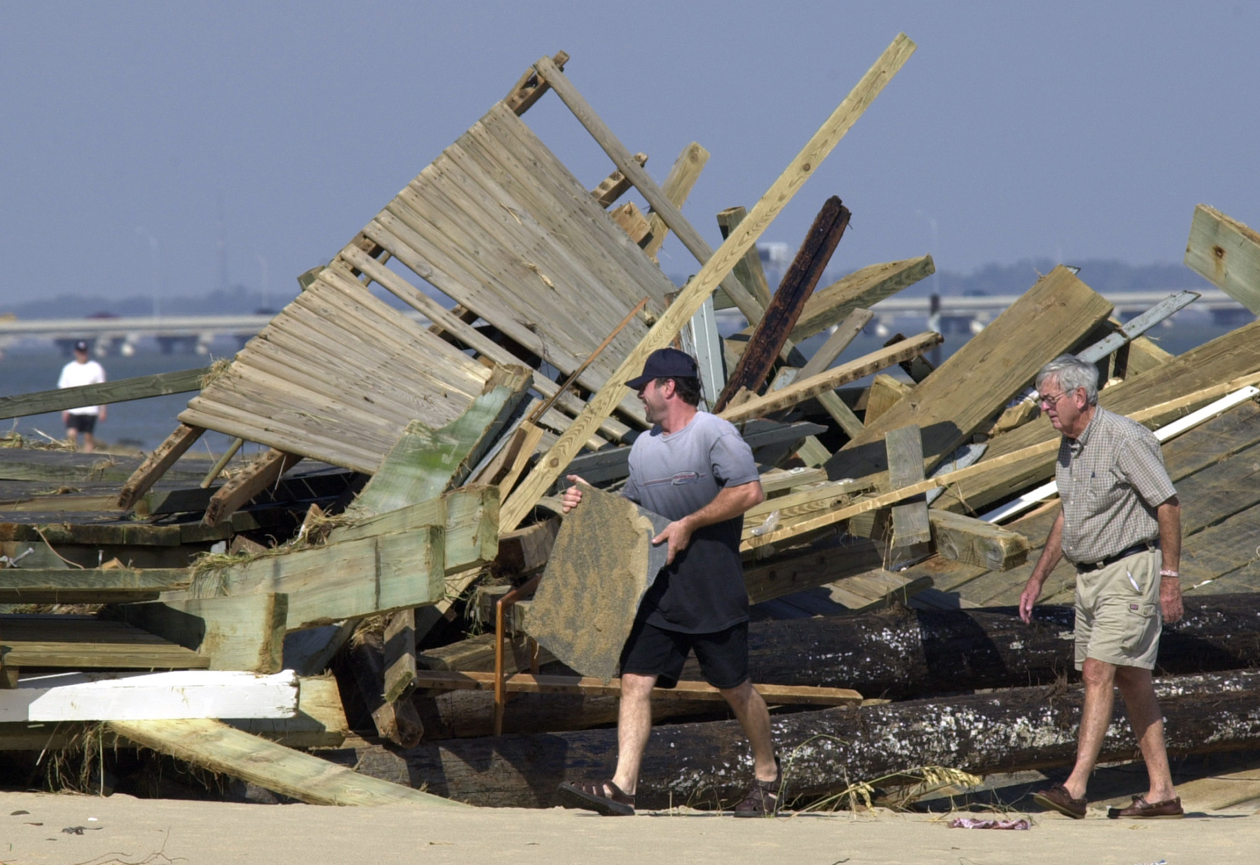 Local residents walk around a section of Harrison fishing pier that washed ashore on the beach in the Ocean View area of Norfolk, Va., Friday Sept. 19, 2003. The pier was built in the 1940's and was destroyed by Hurricane Isabel.  The storm battered the area leaving over 3.5 million people without power.   (AP Photo/Steve Helber)