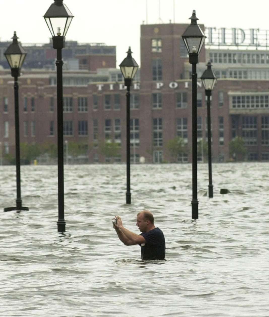 **TRANSMITTED AS AN ALTERNATE CROP**The tide is certainly in,  as a man in flood waters over his waist takes photographs of the flooding in Baltimore's Fells Point Friday, Sept. 19, 2003, where Hurricane Isabel caused much of the city's downtown area to flood. In the background is Tide Point, an office complex.(AP Photo/ Steve Ruark)