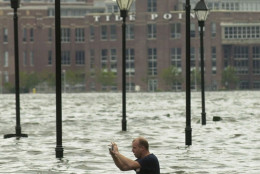 **TRANSMITTED AS AN ALTERNATE CROP**The tide is certainly in,  as a man in flood waters over his waist takes photographs of the flooding in Baltimore's Fells Point Friday, Sept. 19, 2003, where Hurricane Isabel caused much of the city's downtown area to flood. In the background is Tide Point, an office complex.(AP Photo/ Steve Ruark)