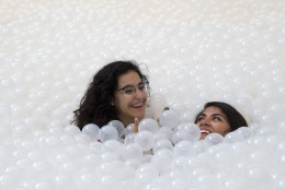 Girls submerge in the ocean at  "The Beach", an interactive architectural installation inside the National Building Museum in Washington, Wednesday, July 29, 2015. The Beach, which spans the length of the museum's Great Hall, was created in partnership with Snarkitecture, and covers 10,000 square feet and includes an ocean of nearly one million recyclable translucent plastic balls.  (AP Photo/Carolyn Kaster)