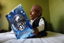 Nepal's Chandra Bahadur Dangi, 72, who says he's only 22 inches (56 centimeters) tall, looks at a copy of the Guinness World Record book at a guesthouse just hours before he was to be measured by officials, in Katmandu, Nepal, Sunday, Feb. 26, 2012. Guinness World Records officials were set to measure Dangi who hopes to be named the world's shortest man Sunday. Dangi is hoping to snatch the title of the world's shortest man from Junrey Balawing of the Philippines, who is 23.5 inches (60 centimeters) tall. (AP Photo/Niranjan Shrestha)