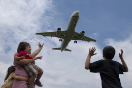 Jyoti Bisbey and her children from left, Ansuya, 5, Arnav, 2, and Mohit, 9, wave from Gravelly Point Park at planes as they roar overhead landing at Ronald Reagan Washington National Airport,  Sunday, June 16, 2013, in Arlington, Va. (AP Photo/Carolyn Kaster)