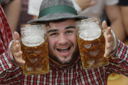 A young man poses with beer mugs at the second weekend in the 'Hofbraeuhaus beer tent' at the famous beer festival Oktoberfest in Munich, southern Germany, Sunday, Sept. 28, 2014. The world's largest beer festival will be held from Sept. 22 to Oct. 5, 2014. (AP Photo/Matthias Schrader)