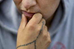 Tattoos decorate the hand and face of Junior Jimenez, of Atlanta, as he listens to Mass conducted by Pope Francis over a loudspeaker along the Benjamin Franklin Parkway outside the Cathedral Basilica of Sts. Peter and Paul Saturday, Sept. 26, 2015, in Philadelphia. (AP Photo/David Goldman)