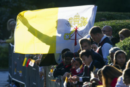 A man holds up a Papal flag as he waits for Pope Francis departure from the Apostolic Nunciature, the Vatican's diplomatic mission in Washington, Wednesday, Sept. 23, 2015. Pope Francis will visit the White House where President Barack Obama will host a state arrival ceremony.  (AP Photo/Cliff Owen)