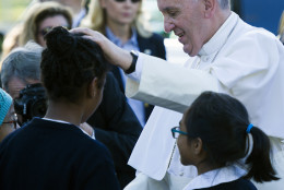 Pope Francis places his hand on the head of a girl as he greets school children prior to departing the Apostolic Nunciature, the Vatican's diplomatic mission in the heart of Washington, Wednesday, Sept. 23, 2015. Pope Francis will visit the White House, becoming only the third pope to visit the White House.  (AP Photo/Cliff Owen)