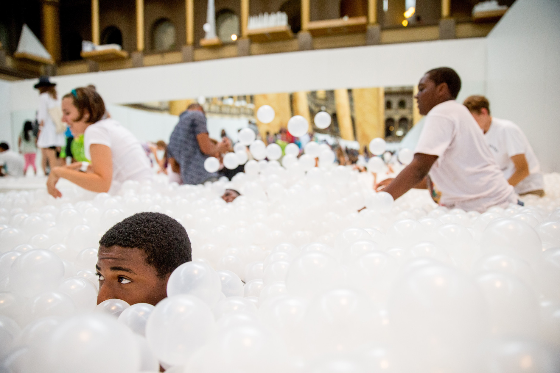 People play at "The Beach", an interactive architectural installation inside the National Building Museum in Washington, Friday, July 17, 2015. The Beach, which spans the length of the museum's Great Hall, was created in partnership with Snarkitecture, and covers 10,000 square feet and includes an ocean of nearly one million recyclable translucent plastic balls. (AP Photo/Andrew Harnik)