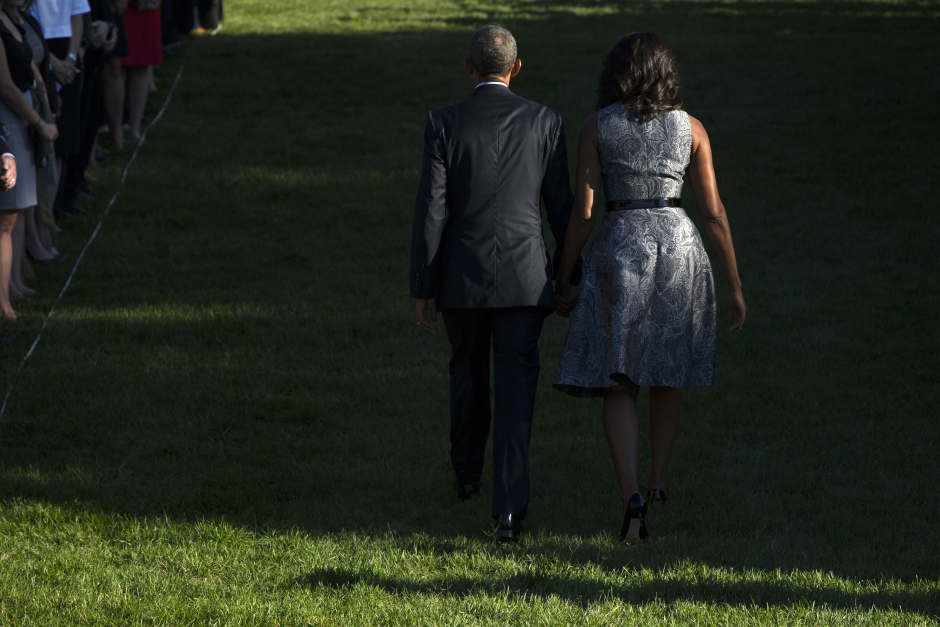 President Barack Obama and first lady Michelle Obama walk off the South Lawn of the White House in Washington, Friday, Sept. 11, 2015, after they observed the 14th anniversary of the 9/11 terrorists attacks. (AP Photo/Evan Vucci)