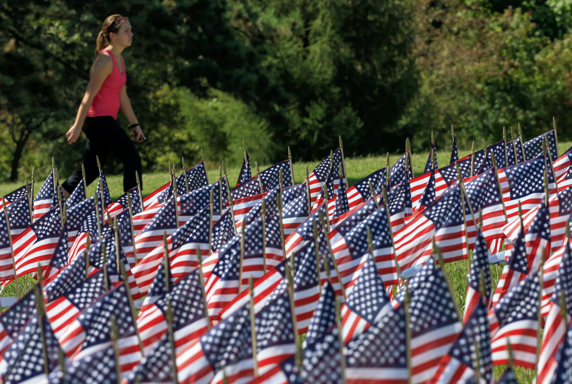 A pedestrian walks Thursday, Sept. 10, 2015, past flags carrying the names of the victims of the Sept. 11 attacks in Omaha, Neb. The flags were placed at Memorial Park as a tribute to the fallen. (AP Photo/Nati Harnik)