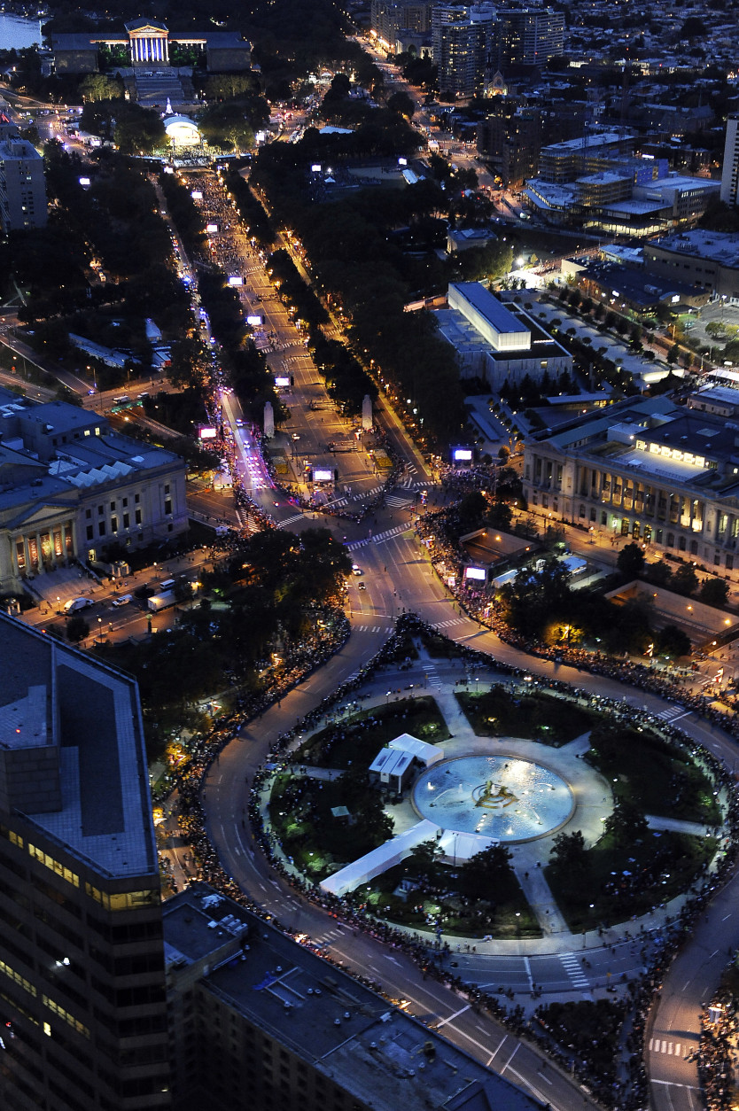 Benjamin Franklin Parkway in Philadelphia is lit up at dusk and lined with tens of thousands of people as Pope Francis makes his way along the thoroughfare, Saturday, Sept. 26, 2015. The pontiff attended a music-and-prayer festival there Saturday night to close out the World Meeting of Families, a Vatican-sponsored conference of more than 18,000 people from around the world. (AP Photo/Michael Perez)