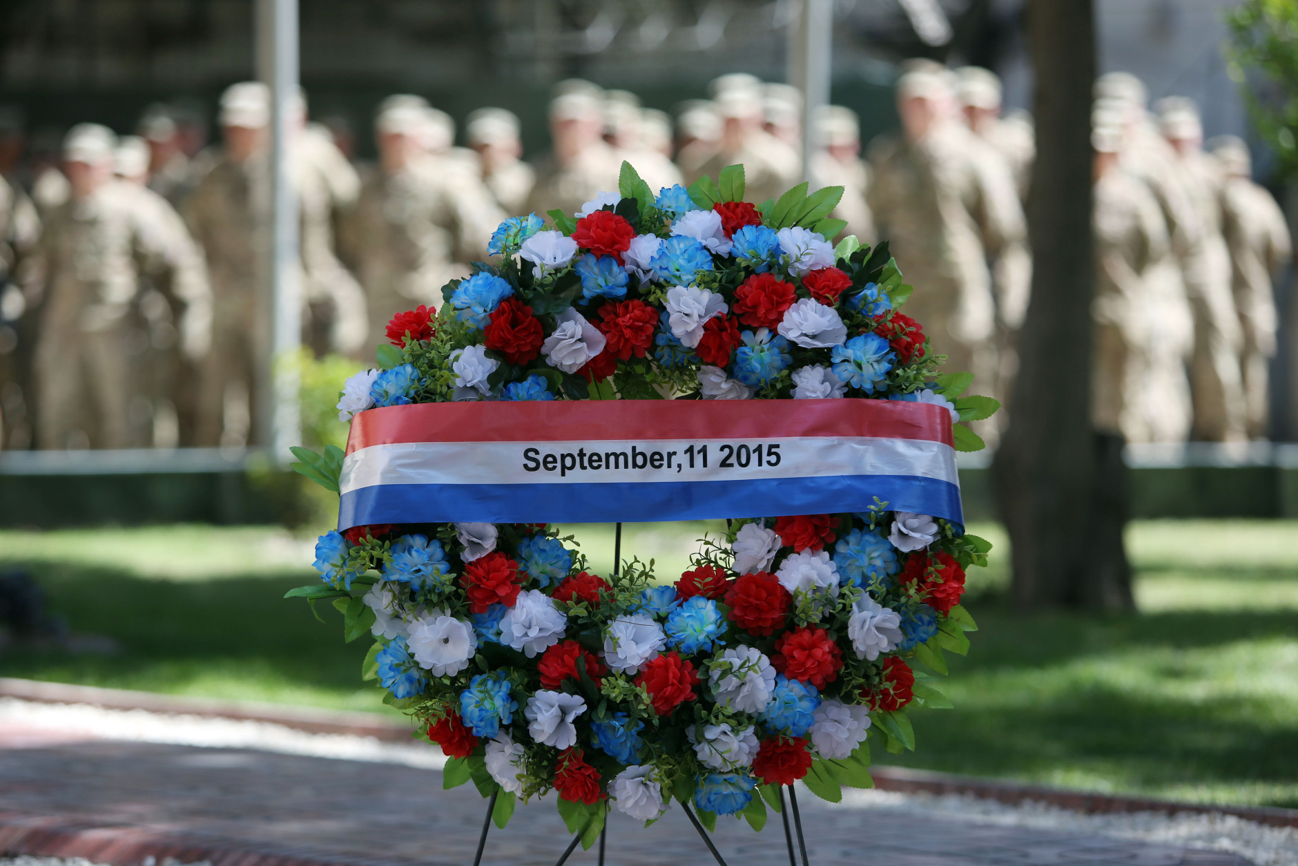 NATO forces stand behind a wreath during a memorial ceremony on the fourteenth anniversary of the 9-11 terrorist attacks on the United States at the headquarters of the International Security Assistance Force, in Kabul, Afghanistan, Friday, Sept. 11, 2015. (AP Photo/Rahmat Gul)