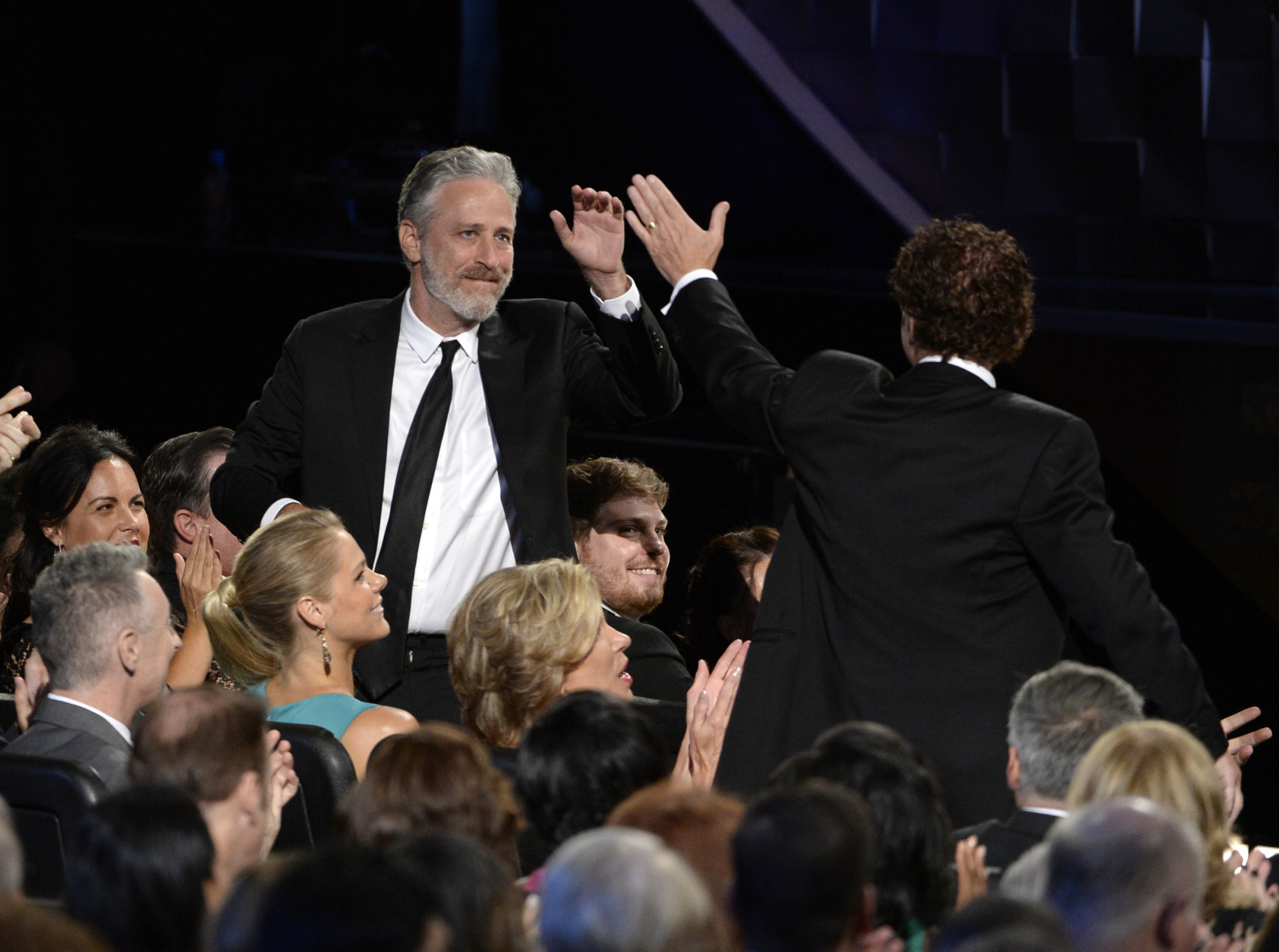 Jon Stewart gives Chuck O'Neil a high five at the 67th Primetime Emmy Awards on Sunday, Sept. 20, 2015, at the Microsoft Theater in Los Angeles. (Photo by Phil McCarten/Invision for the Television Academy/AP Images)