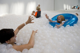 Emma Keyes, left, and Ciara Jacobs, right, toss plastic balls at "The Beach", an interactive architectural installation inside the National Building Museum in Washington, Wednesday, July 29, 2015. The Beach, which spans the length of the museum's Great Hall, was created in partnership with Snarkitecture, and covers 10,000 square feet and includes an ocean of nearly one million recyclable translucent plastic balls. (AP Photo/Carolyn Kaster)