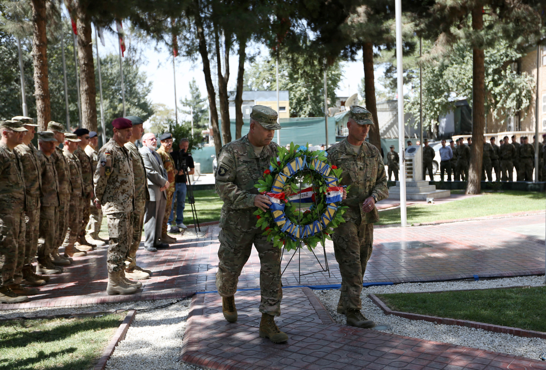Commander of the International Security Assistance Force (ISAF), Gen. John Campbell, left, and Command Sergeant Major Delbert Byers, right, carry a wreath during a memorial ceremony on the fourteenth anniversary of the 9-11 terrorist attacks on the United States at the headquarters of the International Security Assistance Force, in Kabul, Afghanistan, Friday, Sept. 11, 2015. (AP Photo/Rahmat Gul)