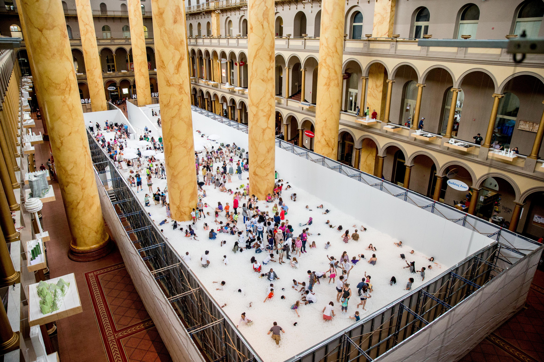 Visitors enjoy "The Beach", an interactive architectural installation inside the National Building Museum in Washington, Friday, July 17, 2015. The Beach, which spans the length of the museum's Great Hall, was created in partnership with Snarkitecture, and covers 10,000 square feet and includes an ocean of nearly one million recyclable translucent plastic balls. (AP Photo/Andrew Harnik)