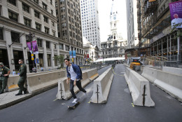 A man on a skateboard rides through a security checkpoint on Broad Street with City Hall in the background in Philadelphia on Friday, Sept. 25, 2015, before Pope Francis' upcoming visit. (AP Photo/Alex Brandon)