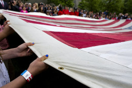 Participants hold The National 9/11 Flag during a ceremony at the 9/11 Memorial in New York Wednesday, May 21, 2014.  The ceremony Wednesday marked the opening of the National September 11 Memorial Museum. After the flag was refolded, firefighters marched it into the museum. The flag was flying from a building near the World Trade Center on Sept. 11, 2001. It was later found shredded in the debris of ground zero. (AP Photo/Craig Ruttle)