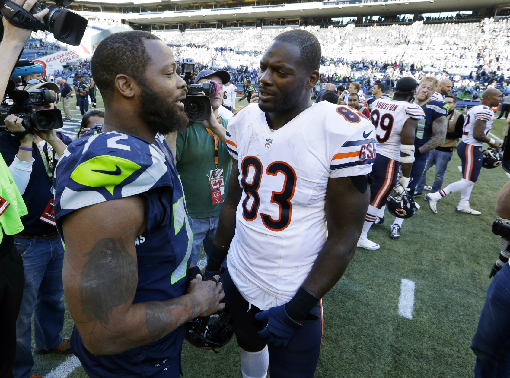 Seattle Seahawks defensive end Michael Bennett, left, talks with his brother, Chicago Bears tight end Martellus Bennett, right, after an NFL football game, Sunday, Sept. 27, 2015, in Seattle. The Seahawks beat the Bears 26-0. (AP Photo/Elaine Thompson)