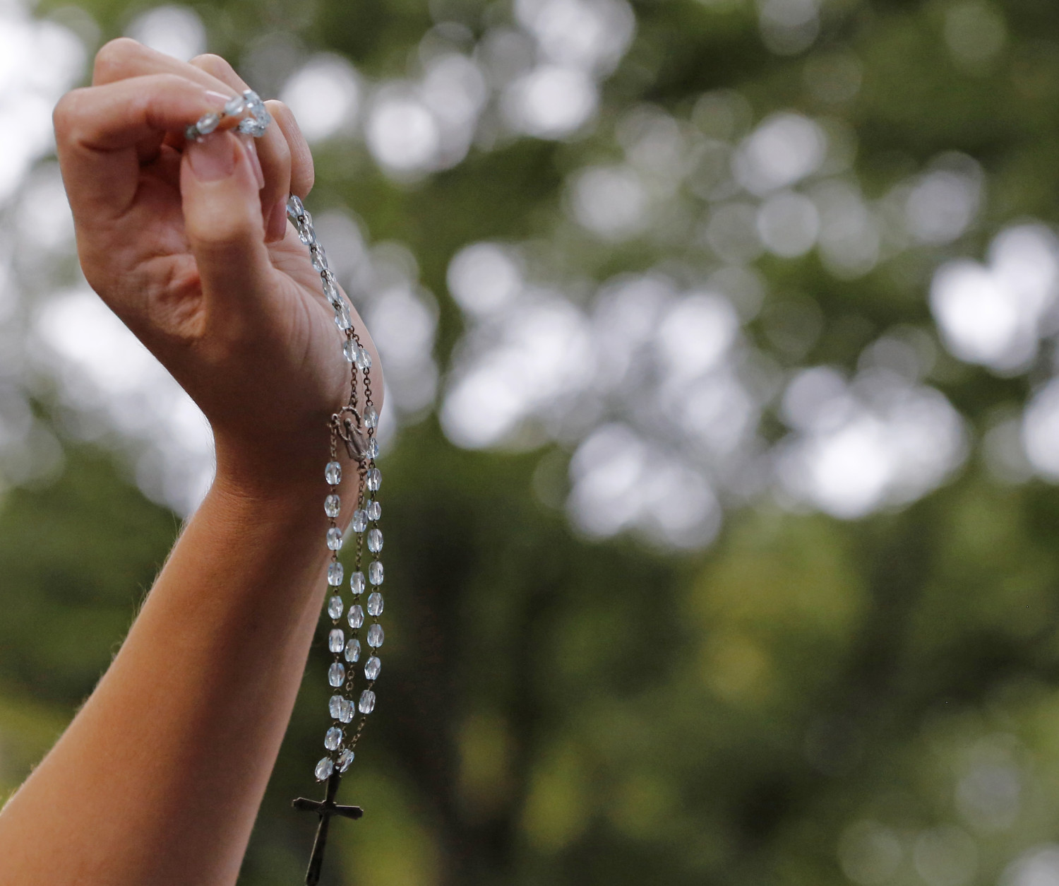 A woman holds up rosary beads as Pope Francis' motorcade passes through Central Park during his visit to New York, Friday, Sept. 25, 2015.  (AP Photo/Kathy Willens)