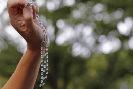 A woman holds up rosary beads as Pope Francis' motorcade passes through Central Park during his visit to New York, Friday, Sept. 25, 2015.  (AP Photo/Kathy Willens)