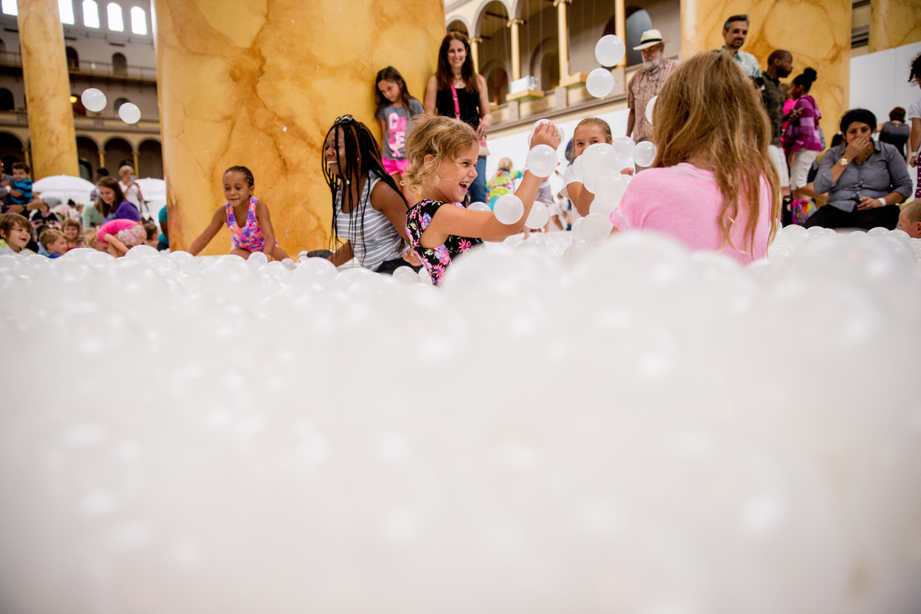 Children play at "The Beach", an interactive architectural installation inside the National Building Museum in Washington, Friday, July 17, 2015. The Beach, which spans the length of the museum's Great Hall, was created in partnership with Snarkitecture, and covers 10,000 square feet and includes an ocean of nearly one million recyclable translucent plastic balls. (AP Photo/Andrew Harnik)