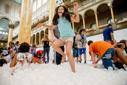 Ilana Cohen, 9, of Alexandria, Va., jumps into a sea of plastic balls at "The Beach", an interactive architectural installation inside the National Building Museum in Washington, Friday, July 17, 2015. The Beach, which spans the length of the museum's Great Hall, was created in partnership with Snarkitecture, and covers 10,000 square feet and includes an ocean of nearly one million recyclable translucent plastic balls. (AP Photo/Andrew Harnik)